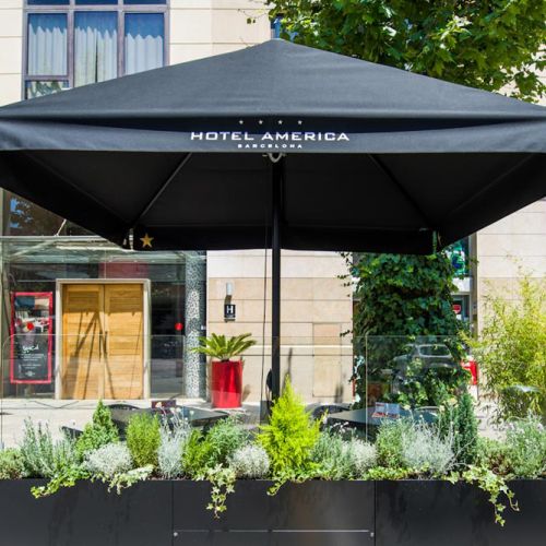 Parasol ibiza d negro con jardinera en terraza de bar