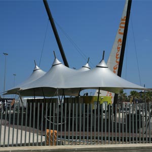 Estructura tensada en forma de carpa de circo con lona gris cubriendo equipamientos