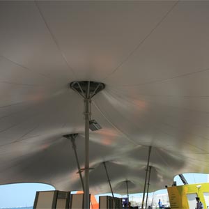 Estructura tensada en forma de carpa de circo con lona gris cubriendo equipamientos