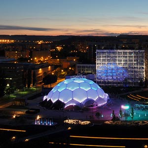 Vista aérea de la ciudad con la cúpula de la plaza milenio con fachada ETFE de noche iluminada en az