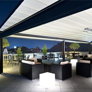 Pérgola cubriendo terraza con mobiliario exterior de noche en Hotel Center